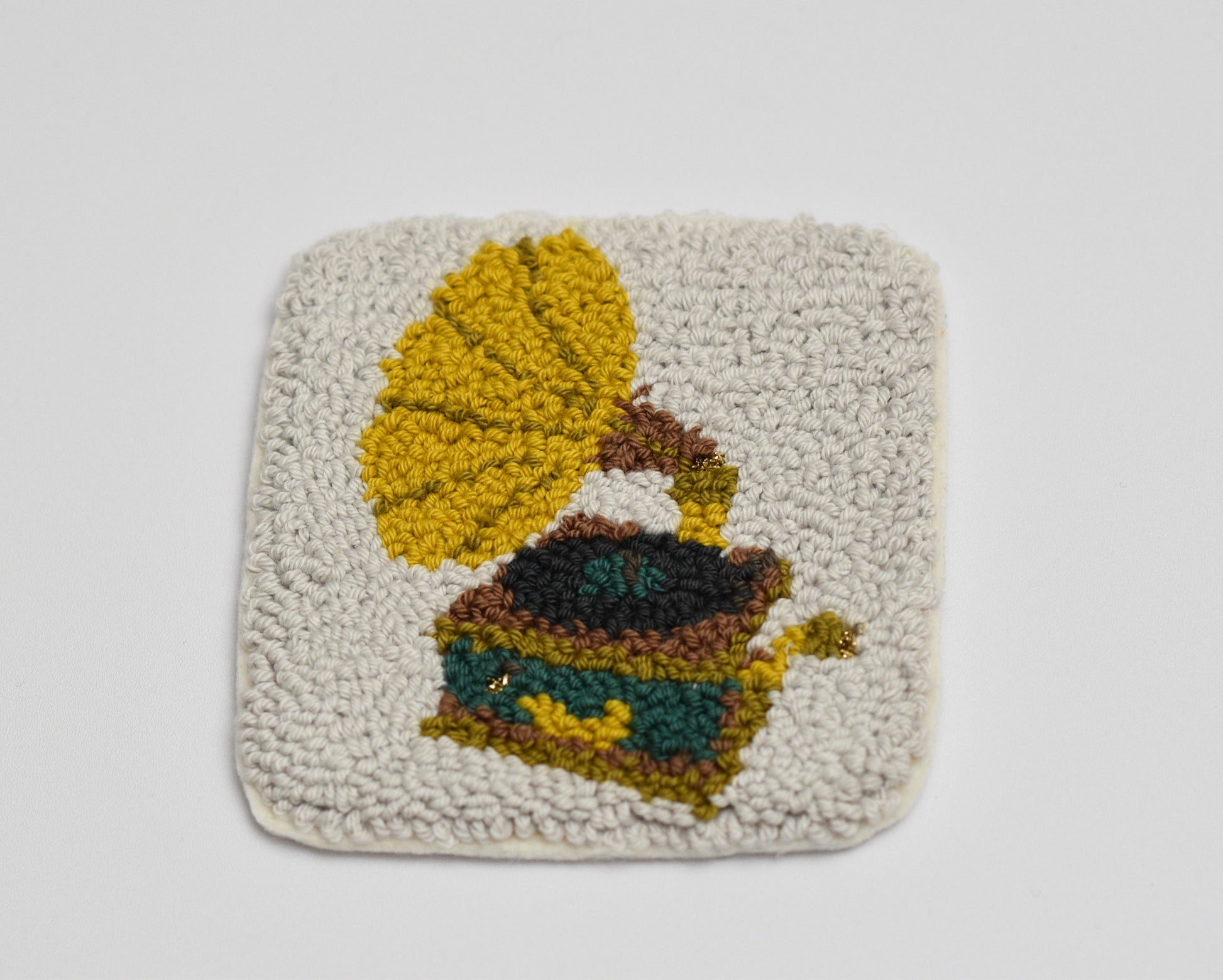 Square punch needle  coaster with a gramophone design on a light gray background