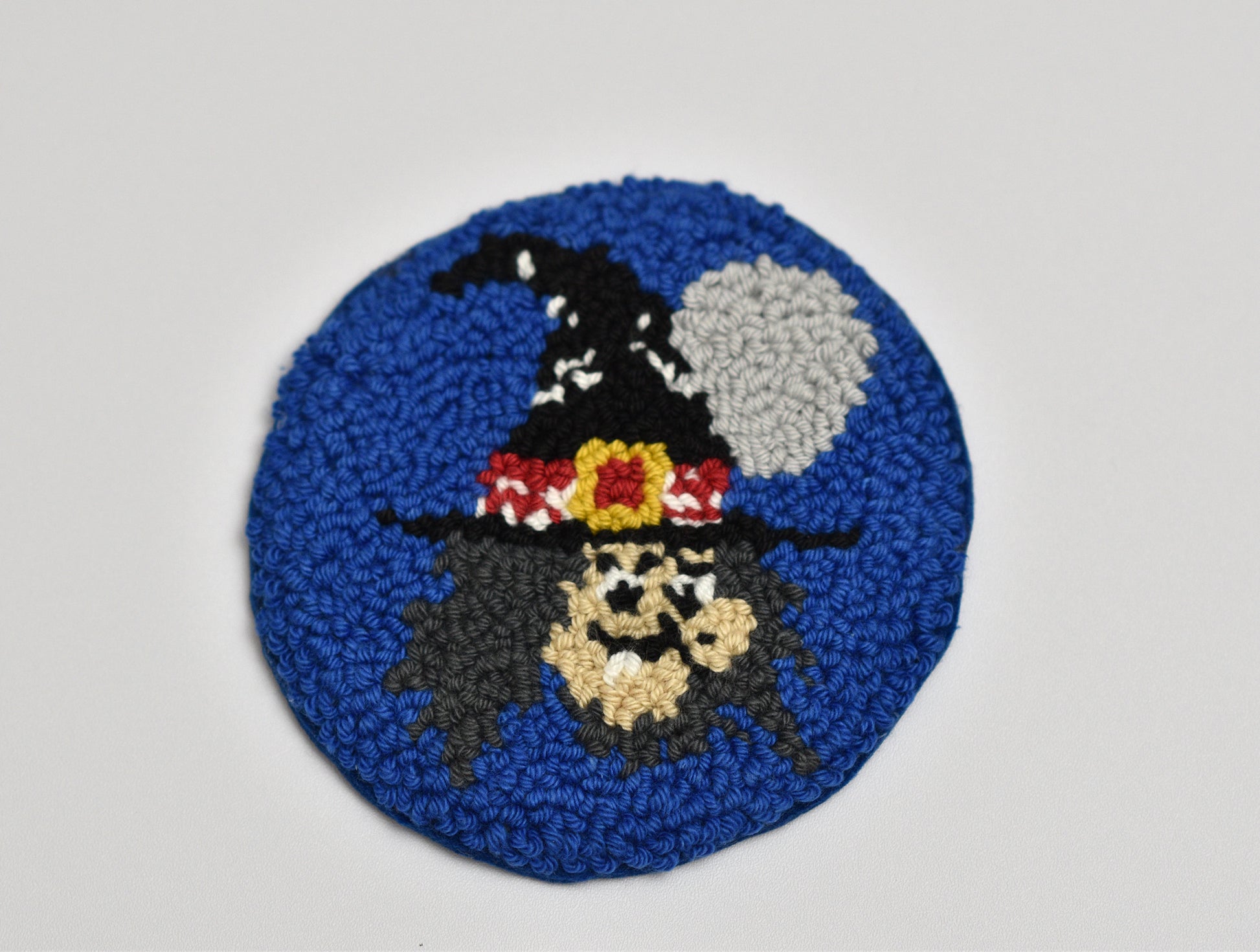 Round blue mug rug with a Witch design on a gray background