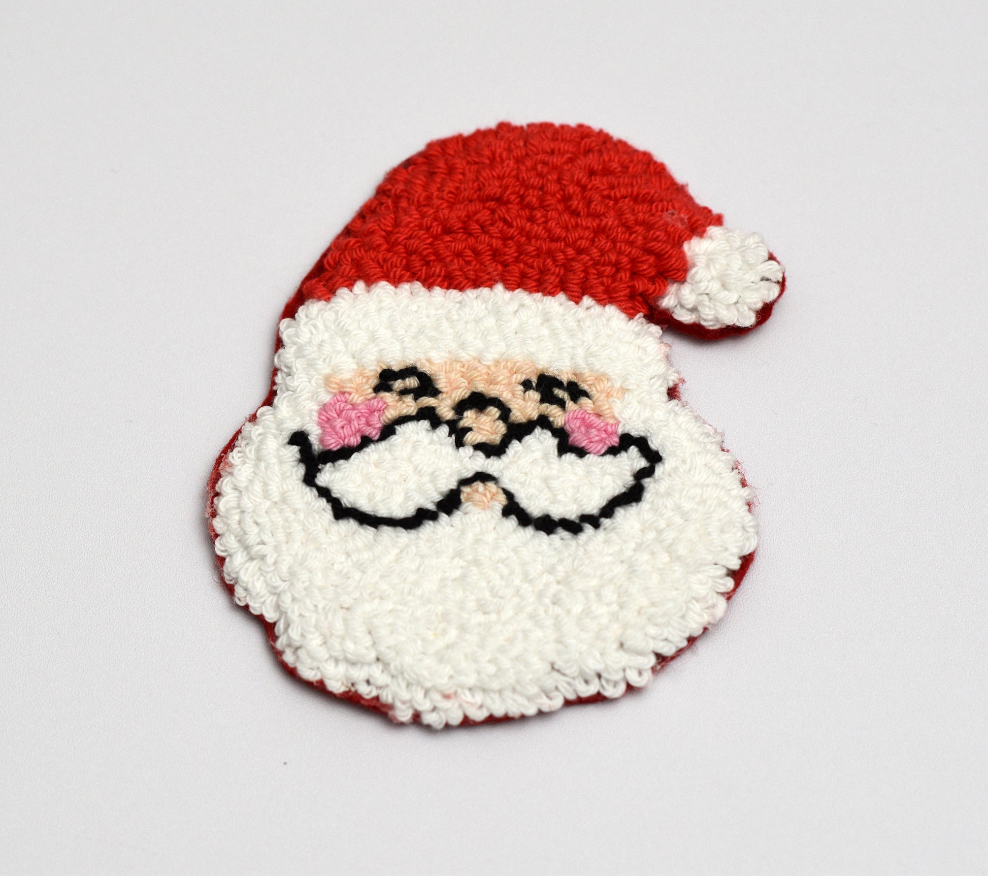 Decorative punch needle coaster with a Santa Claus design on a white background