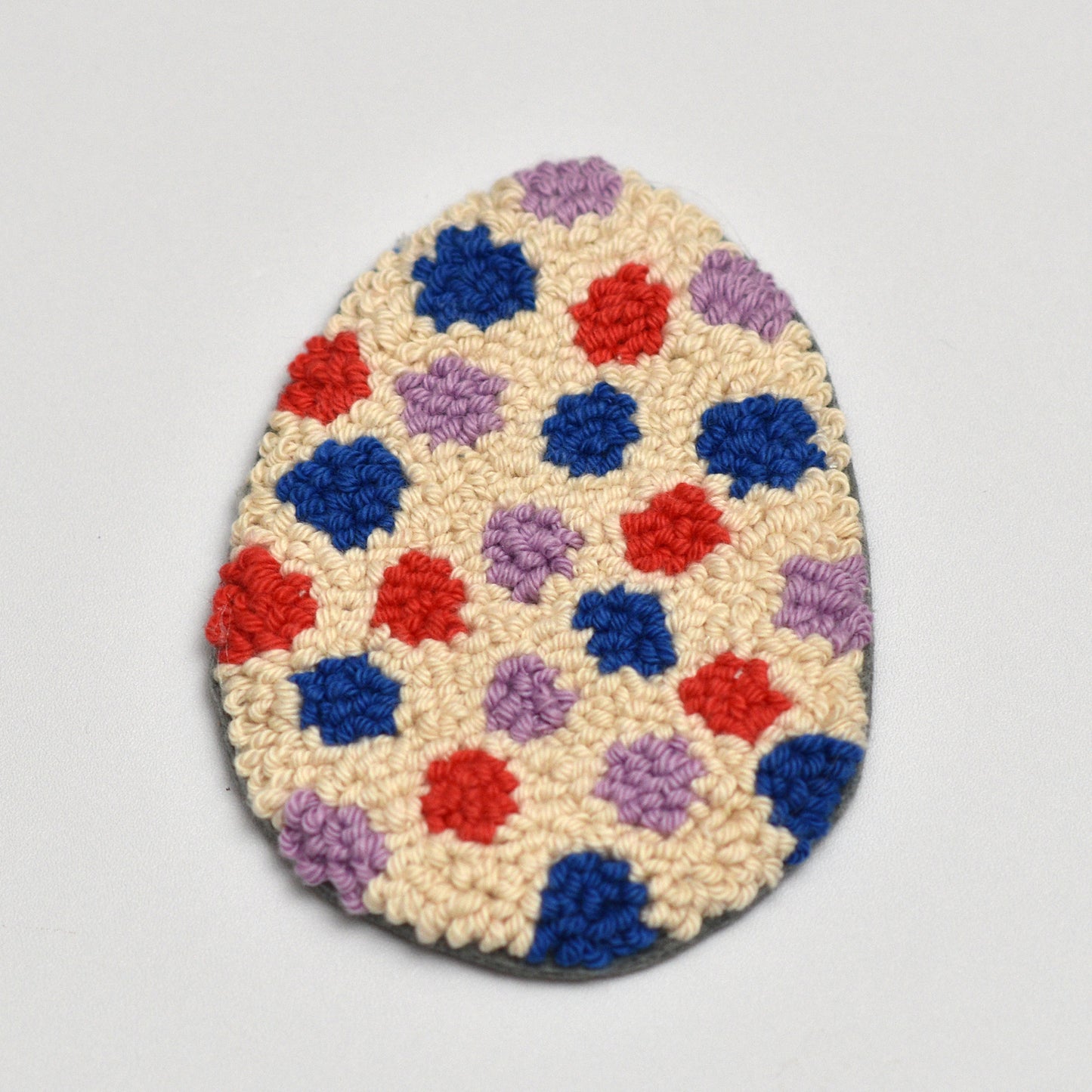 Decorative Easter egg shaped rug with colorful dot patterns on a plain background