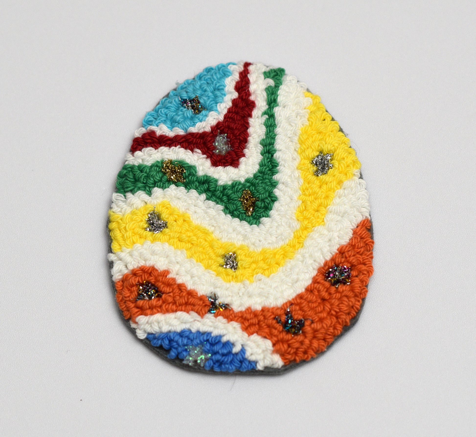 Colorful woven coaster with a zigzag pattern on a white background