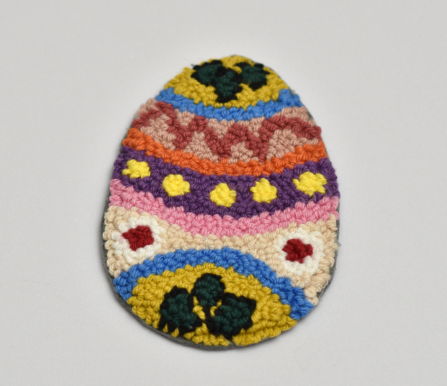 Colorful woven egg-shaped rug on a plain background
