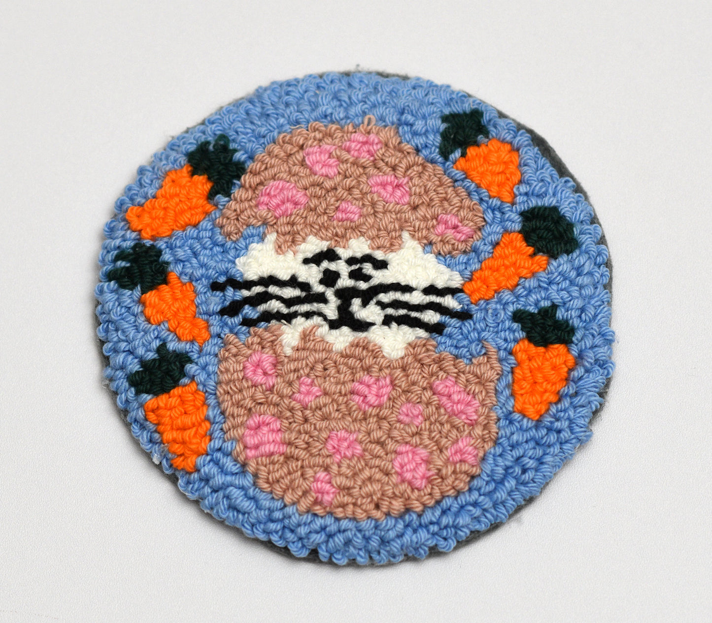 Circular Easter coaster with a Bunny inside Easter Egg design on a blue background