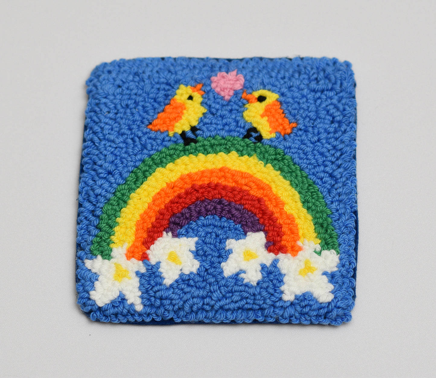 Handmade rug with a rainbow and birds design on a blue background