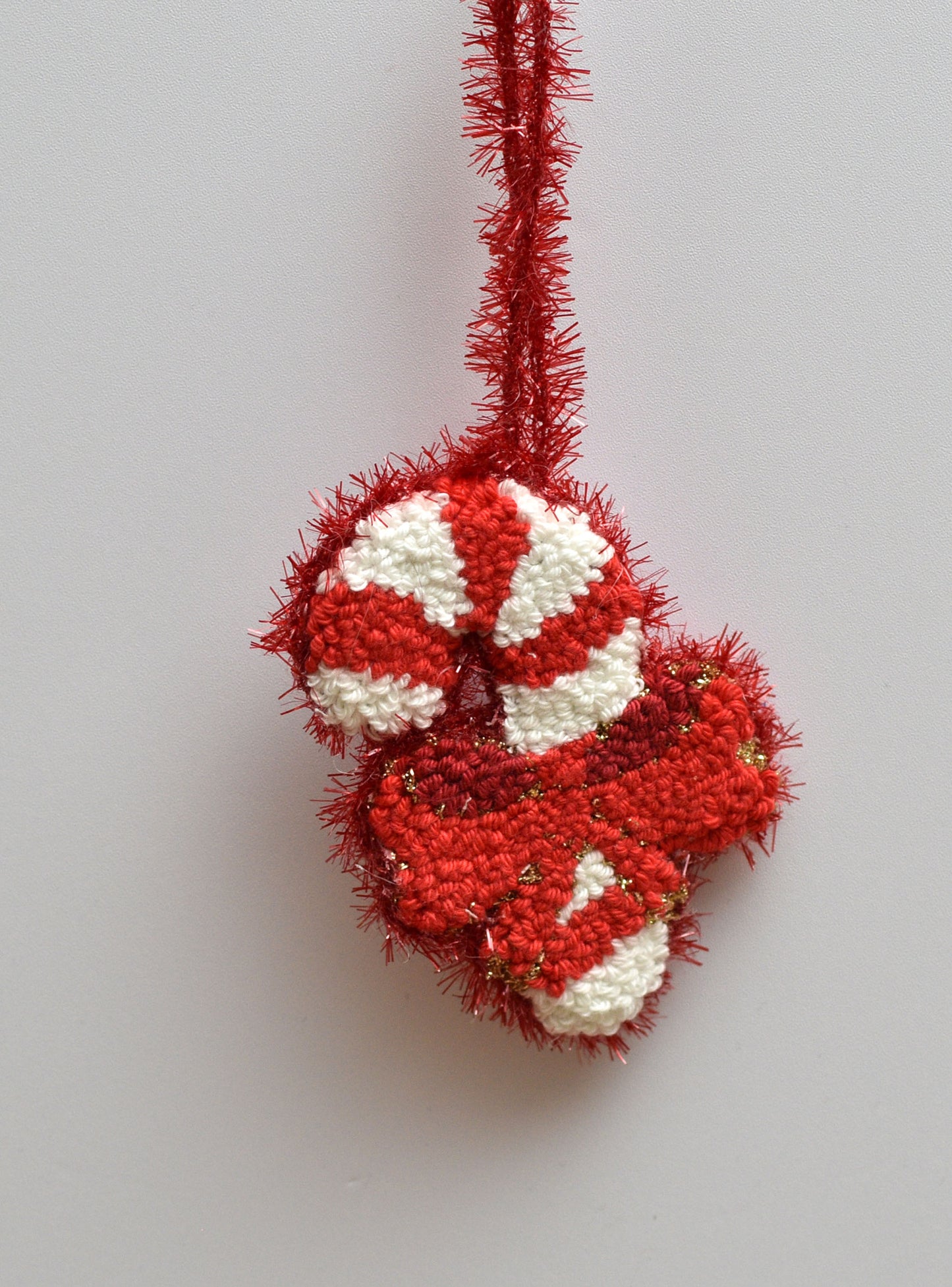 Red and white embroidered candy cane ornament on a light gray background