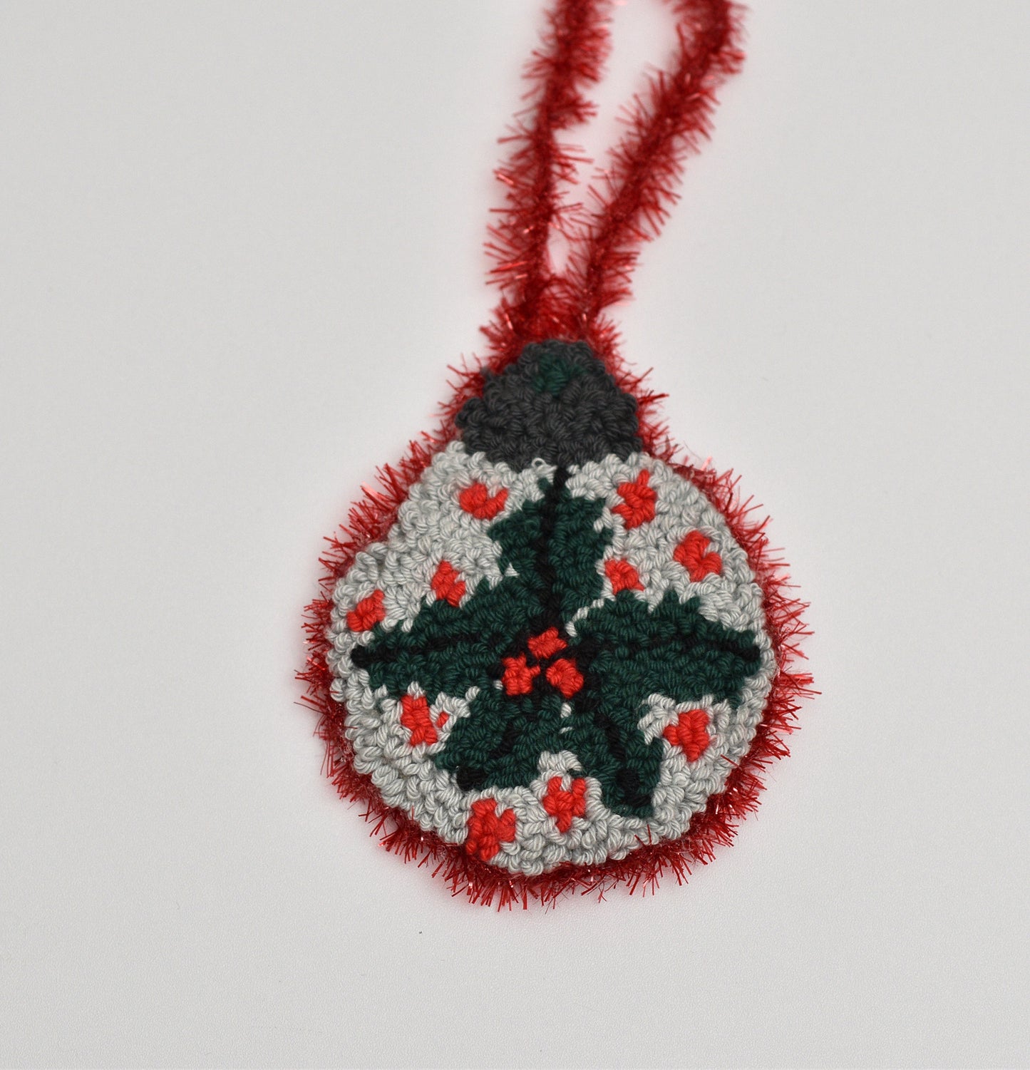 Decorative Christmas ornament with mistletoe design on a plain background