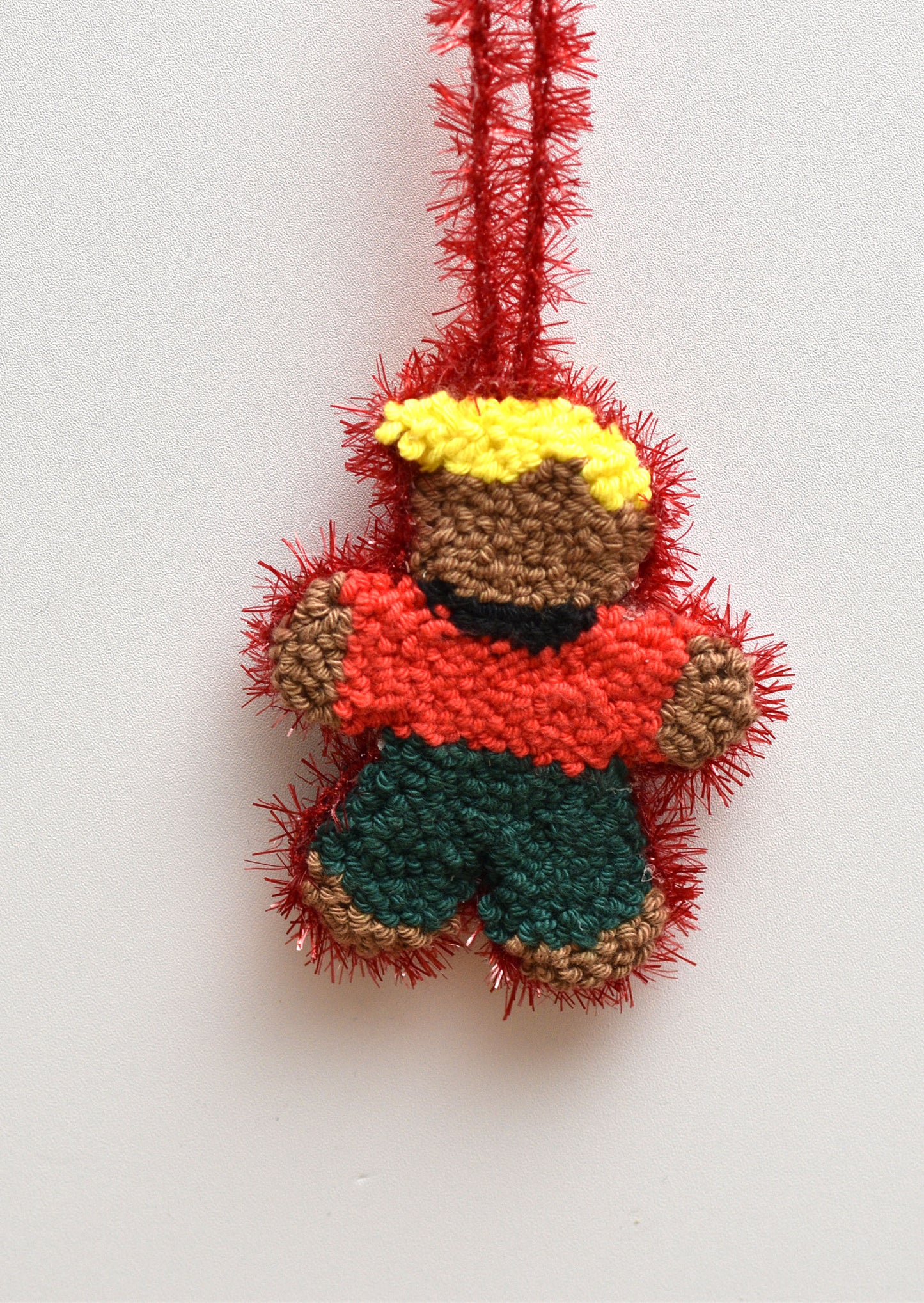 Colorful punch needled gingerbread man ornament on a white background