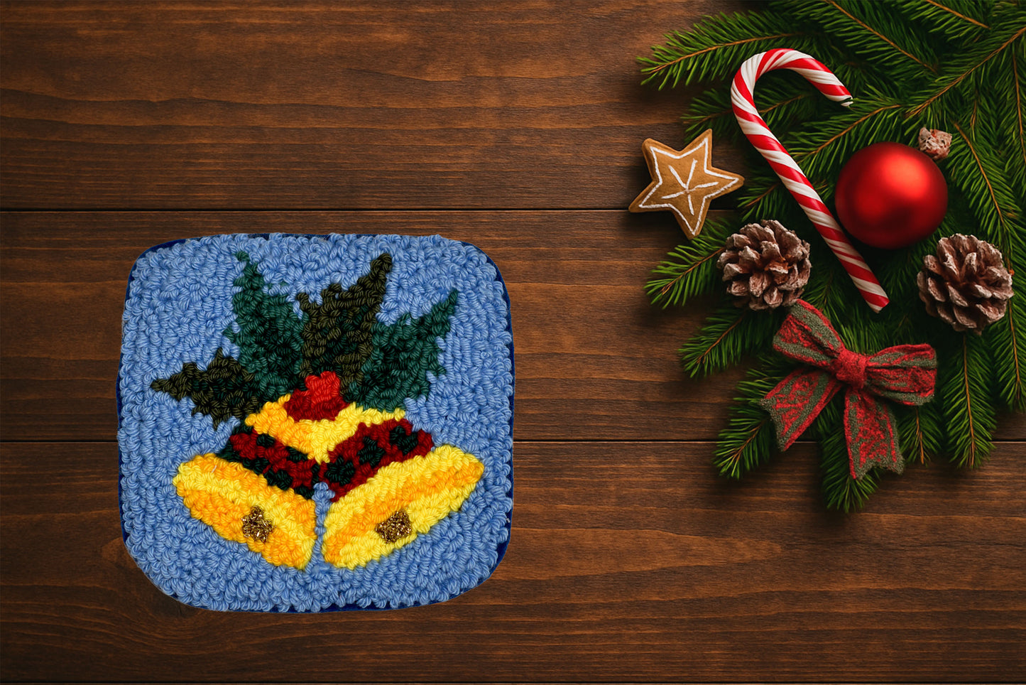 Decorative mug rug with Christmas design next to festive decorations on a wooden surface