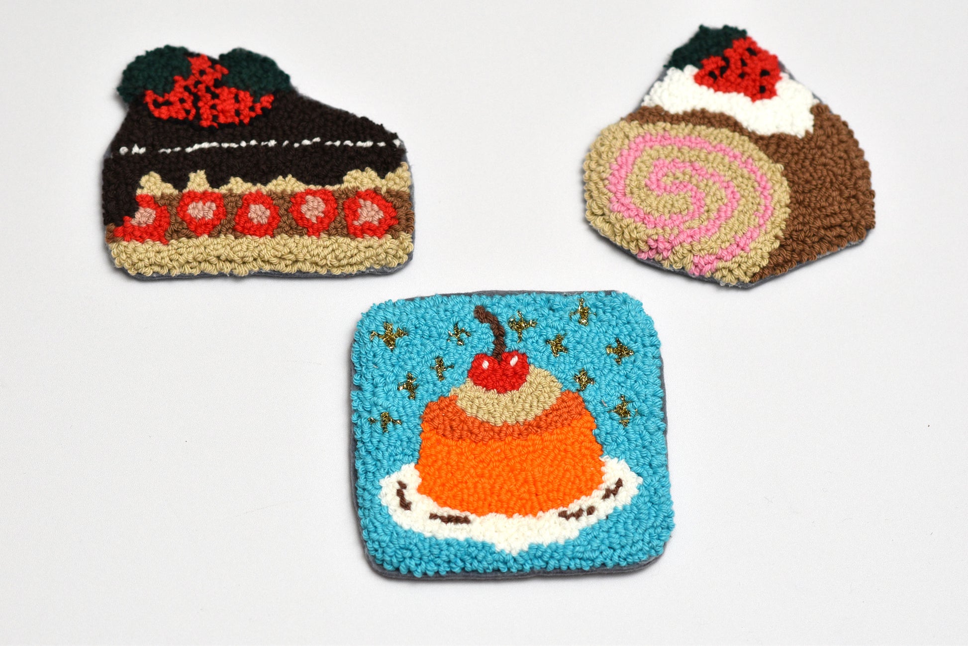 Three knitted items shaped like desserts on a white background
