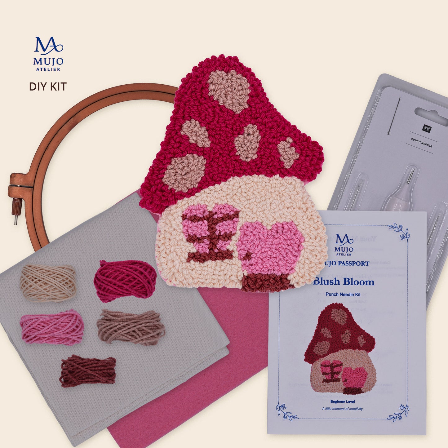 Blush Bloom punch needle DIY kit with pink mushroom house coaster, cotton yarn, fabric, felt, embroidery hoop, punch needle tool and Mujo Passport.