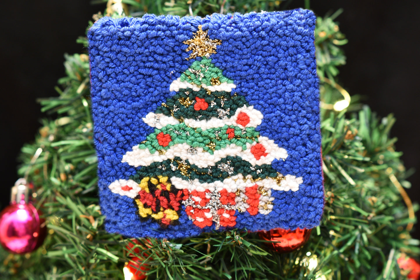 punch needle christmas tree coaster in front of a real christmas tree decoration