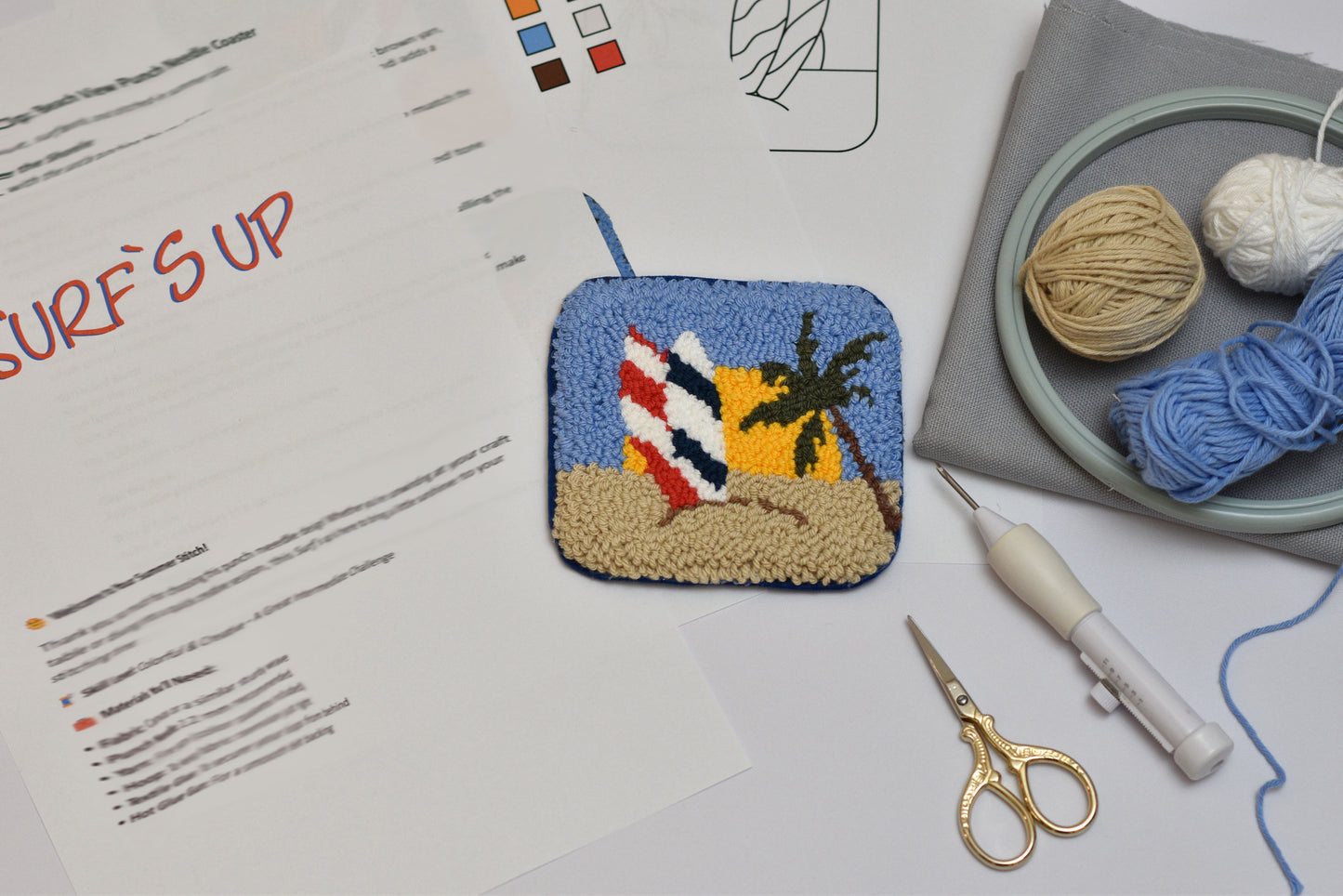Embroidered patch with beach design on a surface with sewing tools and yarn.