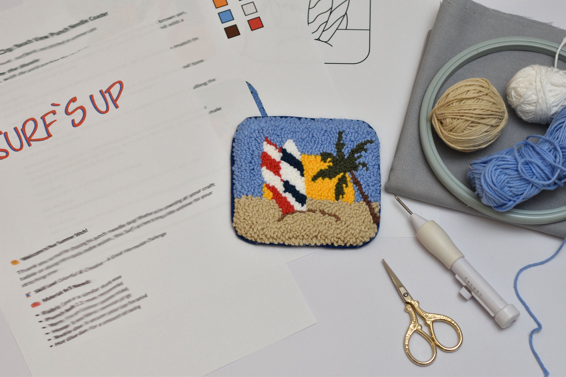 Embroidered patch with beach design on a surface with sewing tools and yarn.