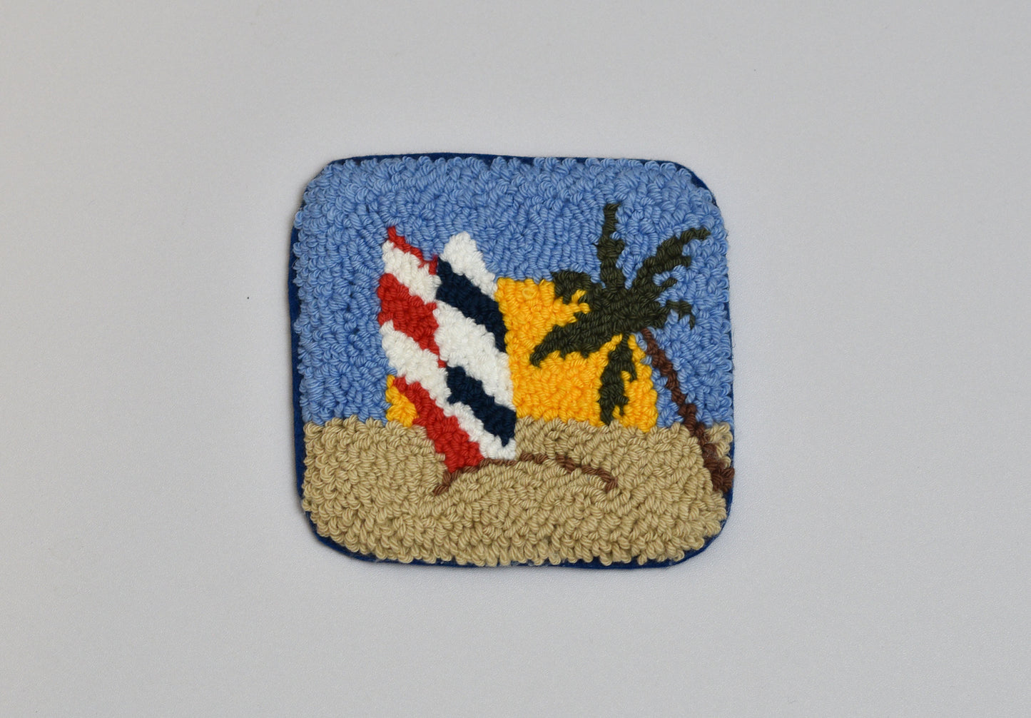 Decorative patch with a beach scene featuring a palm tree and surfboards on a blue background.
