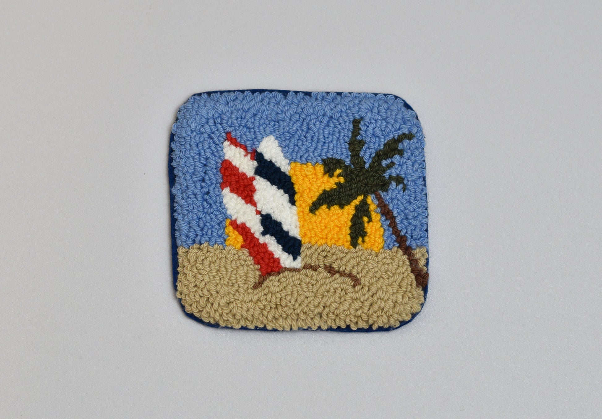Decorative patch with a beach scene featuring a palm tree and surfboards on a blue background.