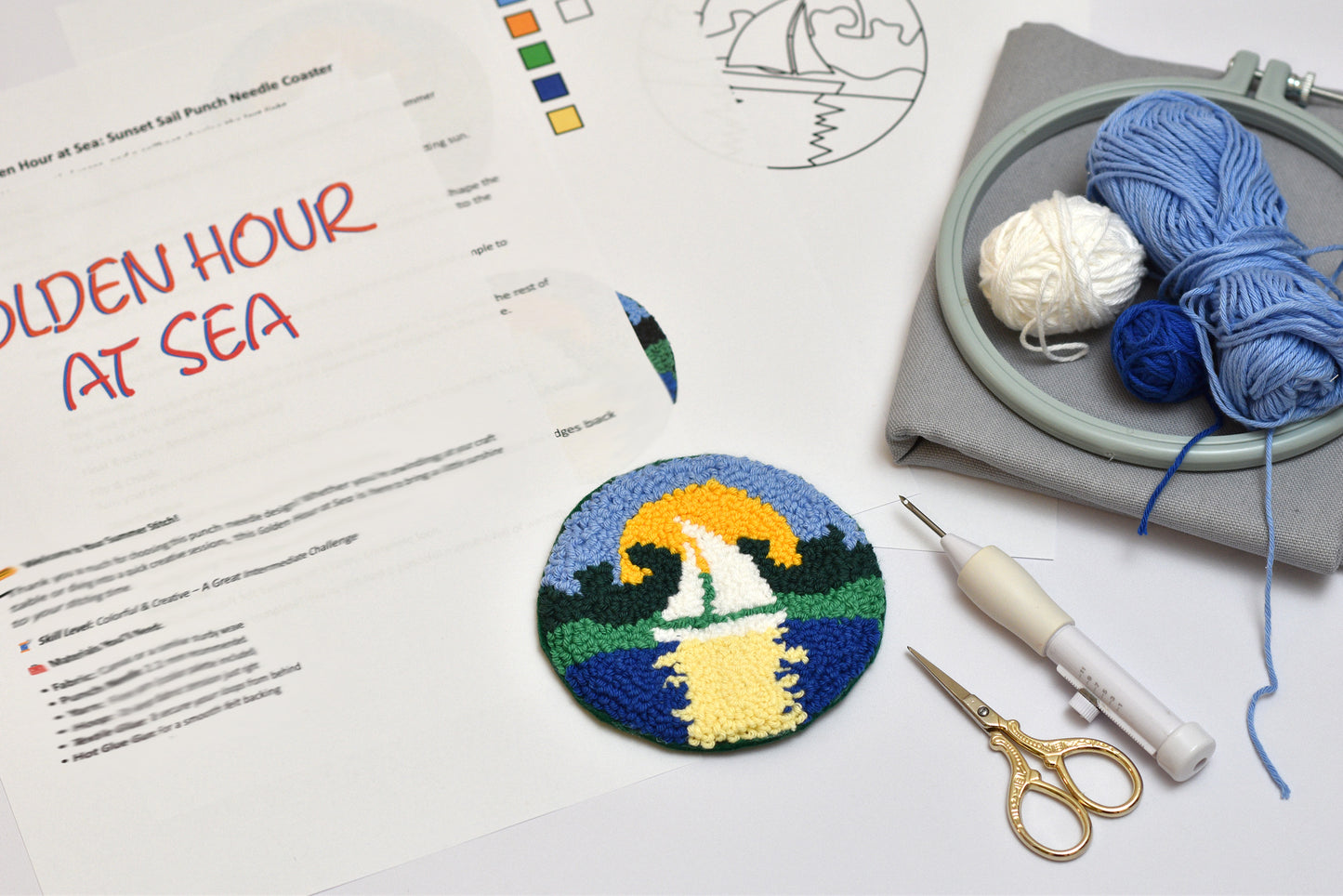 Embroidery hoop with yarn, scissors, and a partially completed embroidery design on a worksheet.