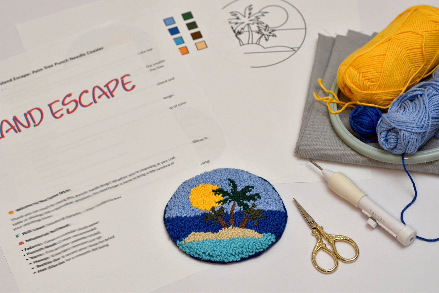 Embroidery kit with a completed patch of an island scene, yarn, scissors, and instructions on a table.