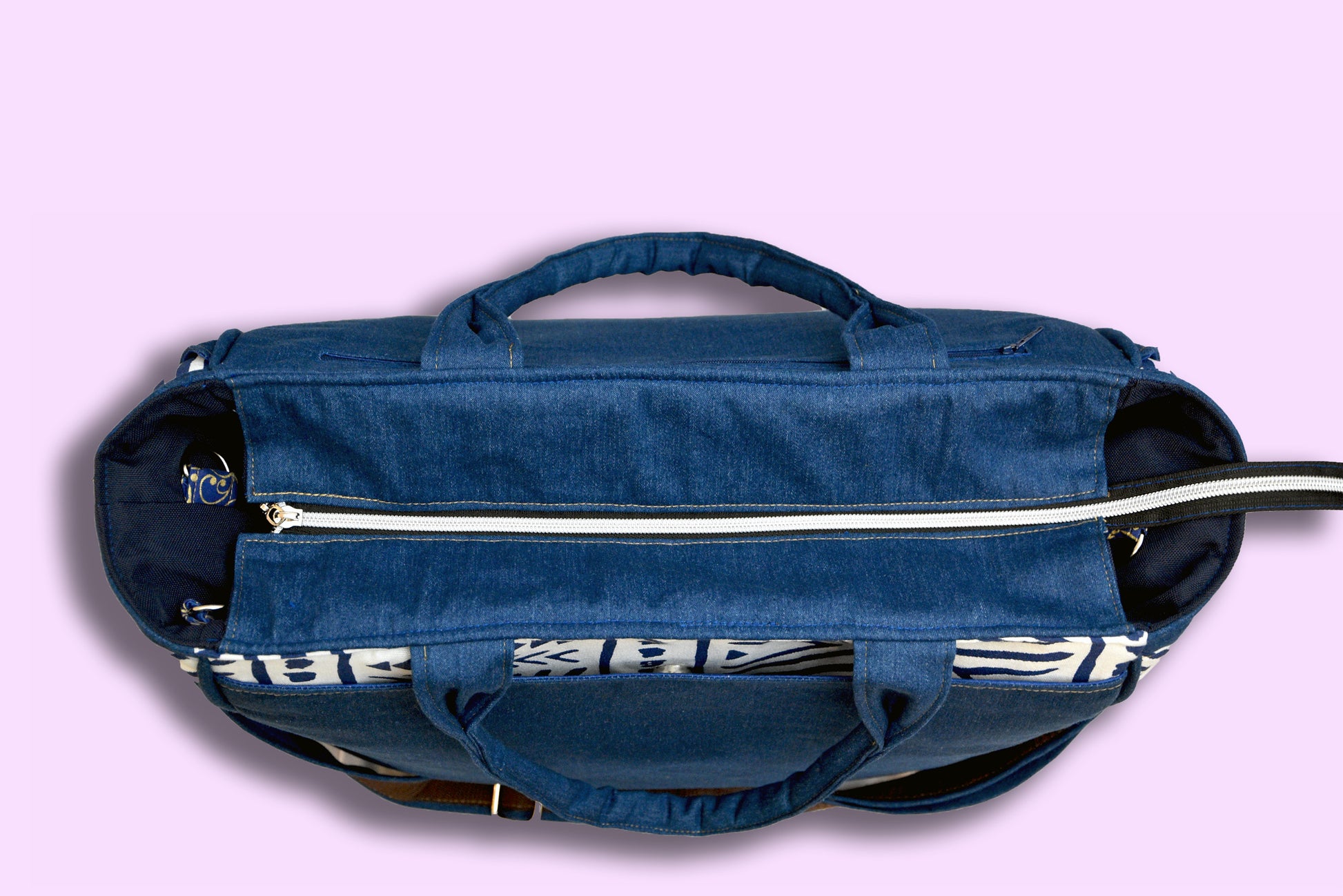 Blue tote bag with zippers on a light purple background