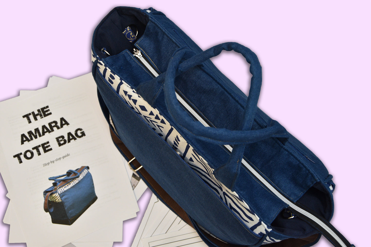 Blue tote bag with white zippers on a light purple background