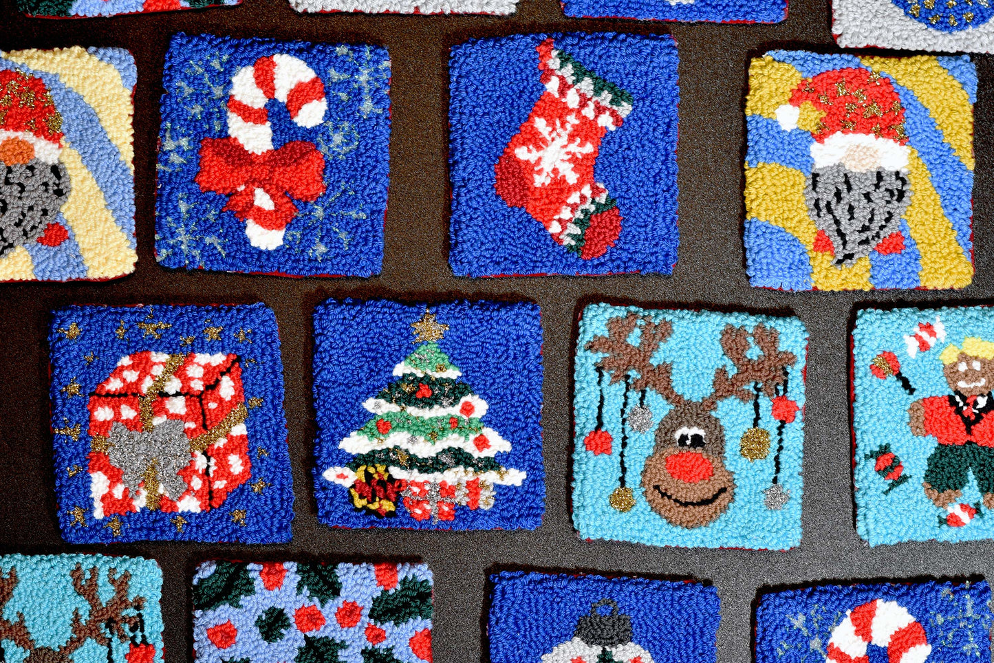 Collection of Christmas-themed square punch needled coaster designs on a fabric background