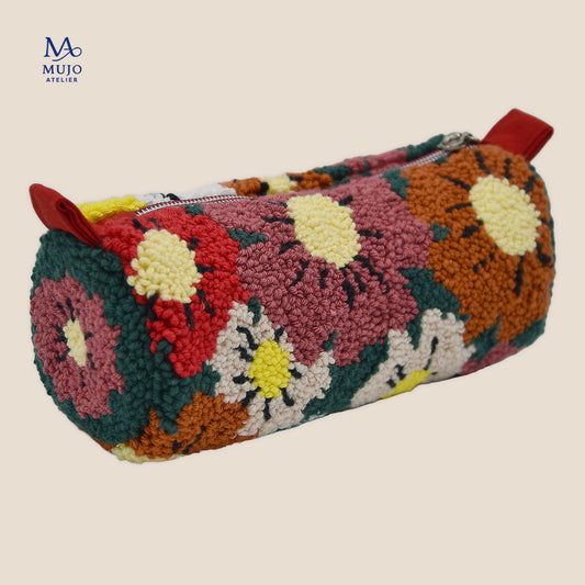 Punch needle zipper pouch with colorful floral pattern in red, dusty pink, yellow, cream and dark green yarn, finished with red tabs and a silver zipper.