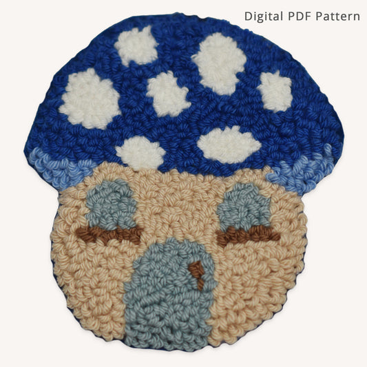 Blue mushroom house punch needle coaster pattern PDF featuring a whimsical cottage-style mushroom home with cloud-like white spots, pale blue windows, and a matching blue door. Beginner-friendly digital punch needle pattern with printable template and instant download.