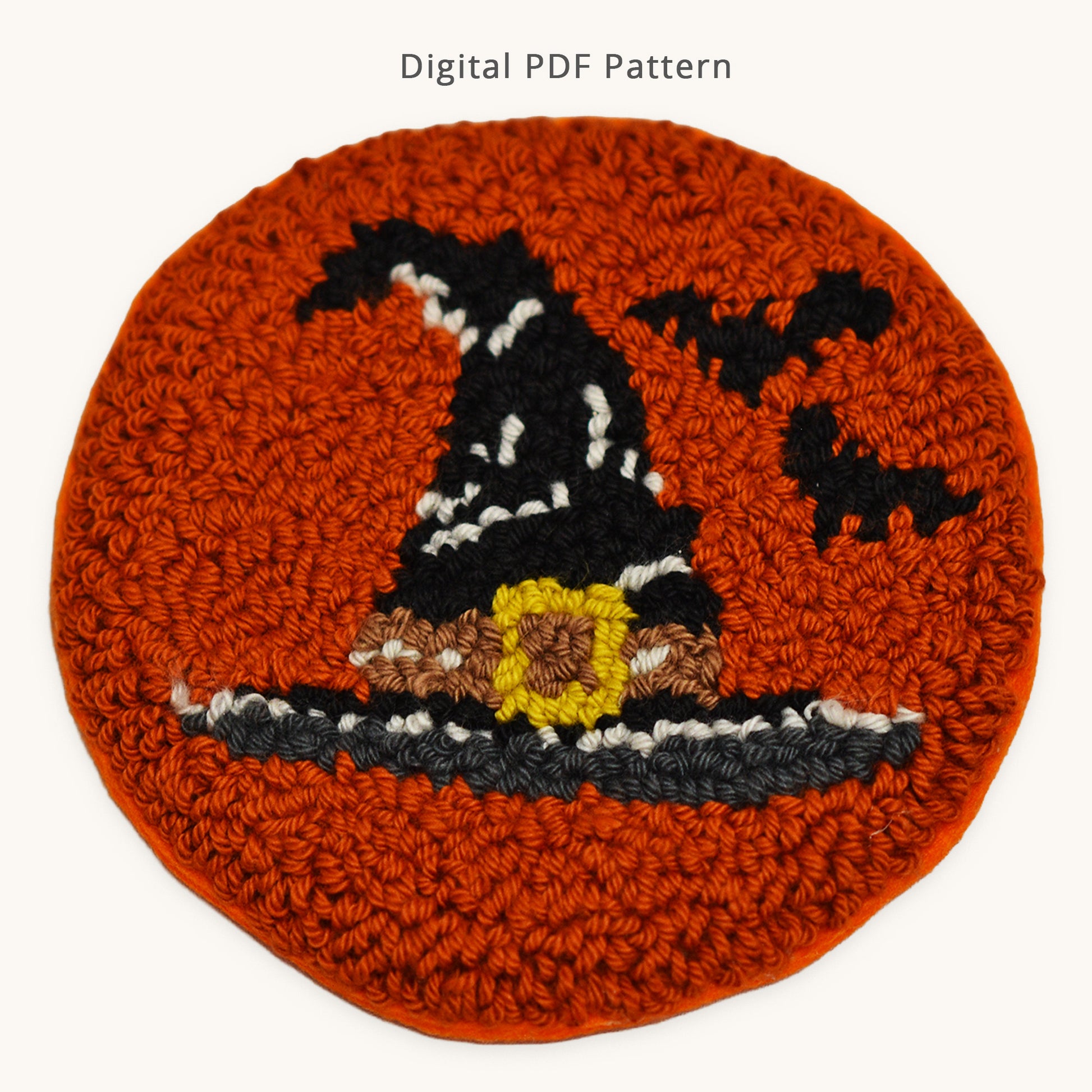 Halloween witch hat punch needle coaster pattern, digital PDF download featuring a black witch hat with buckle and bats on an orange round coaster, beginner-friendly punch needle design.