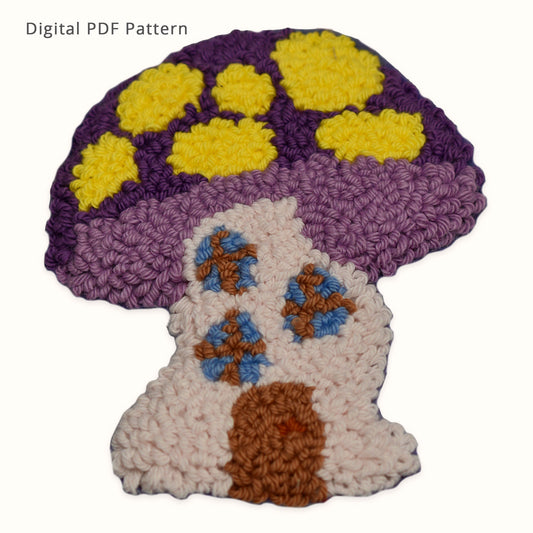 Purple mushroom house punch needle coaster pattern digital download. Whimsical cottage core mushroom home design featuring yellow spots on the cap, blue windows, and a brown door. Beginner-friendly PDF pattern for creating a handmade punch needle coaster.
