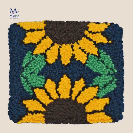 Punch needle sunflower pattern featuring bright yellow sunflowers, green leaves and dark navy background, shown on a warm neutral background.
