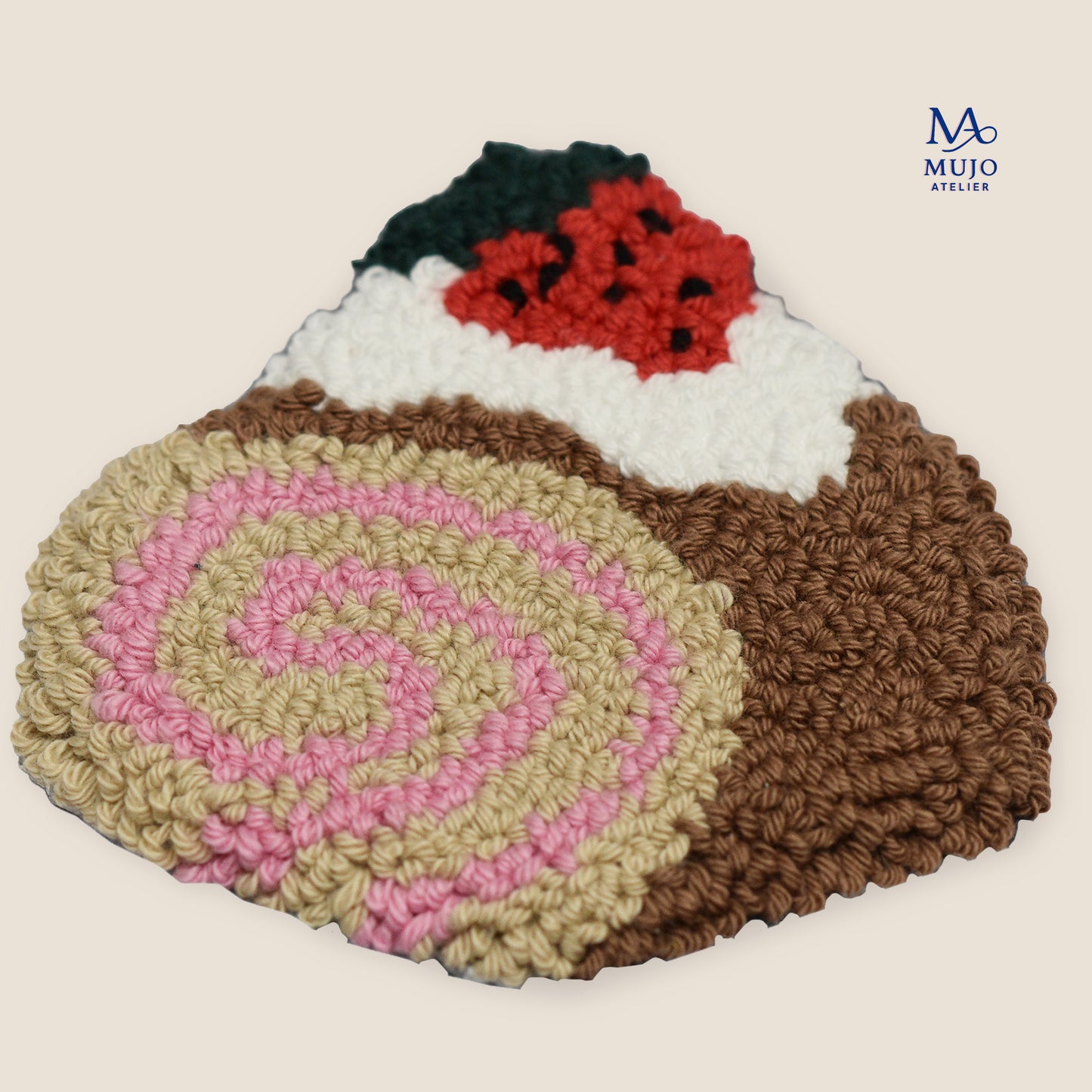 Jam roll cake punch needle pattern featuring a pink cream spiral, chocolate cake, white cream and red berry topping, shown as a textured handmade punch needle project.