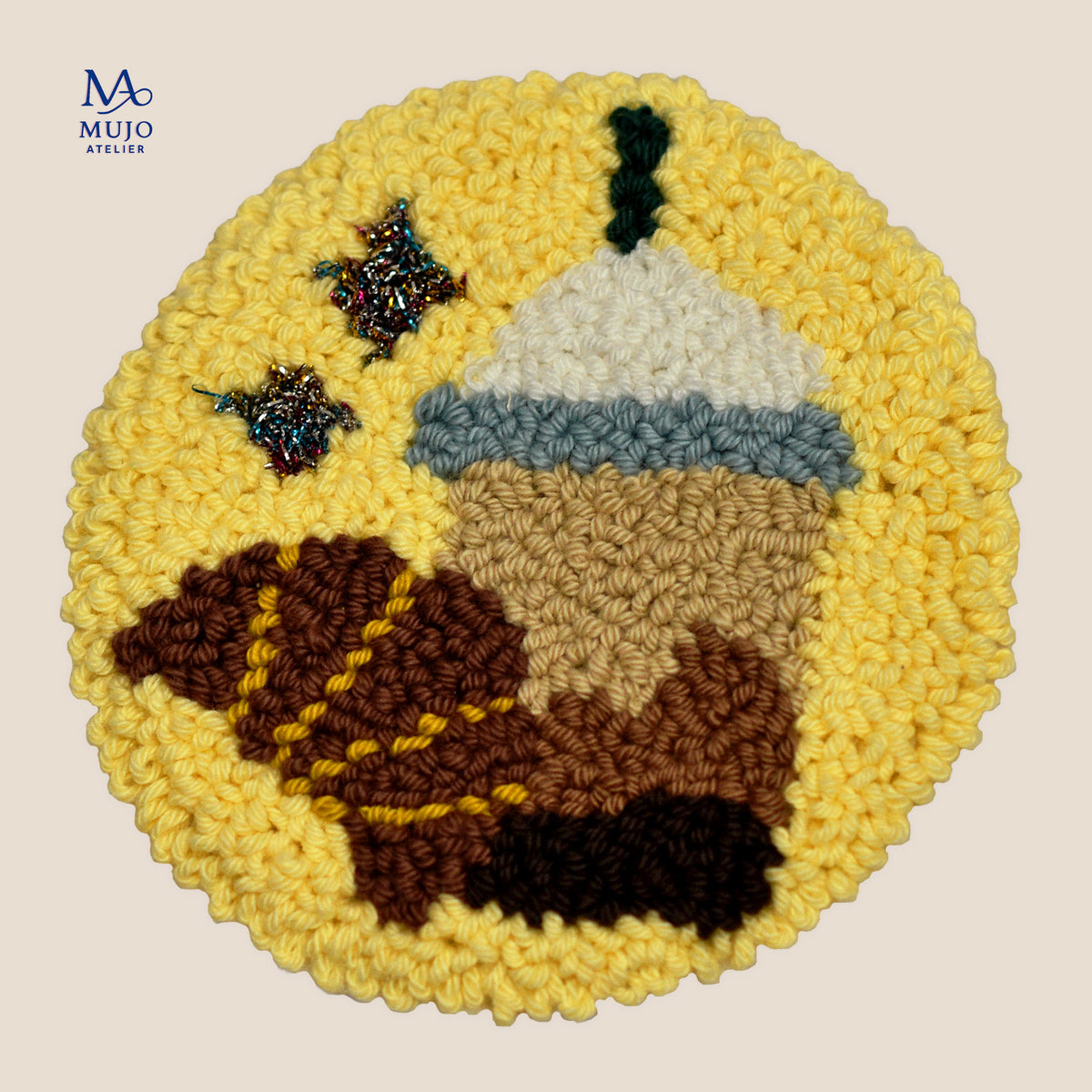 Round punch needle pattern featuring a takeaway coffee cup with a cream lid, brown croissant and sparkly accents on a bright yellow background.