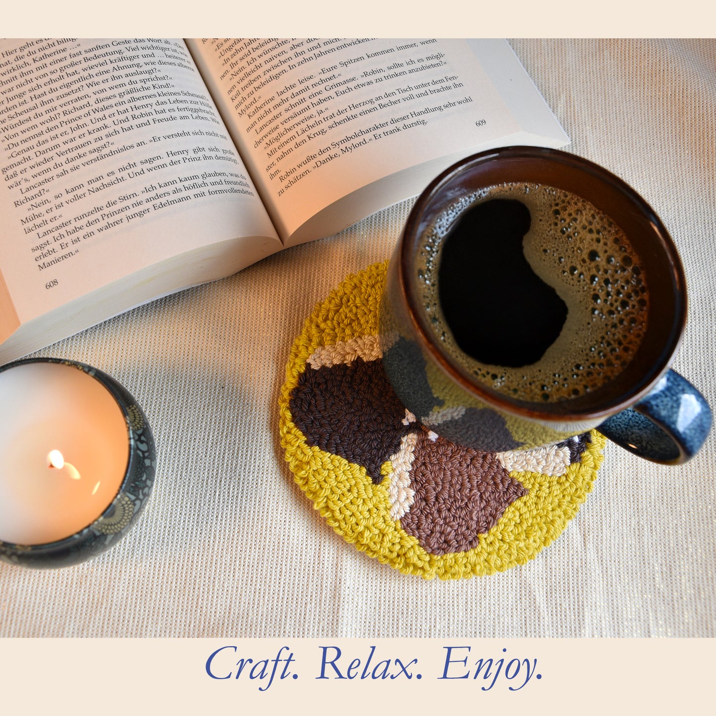 Nutty Warmth chestnut punch needle coaster in use under a coffee mug, styled with a lit candle and open book for a cozy autumn setting.