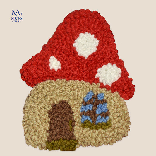 Punch needle mushroom cottage with a bright red cap, white spots, cream walls, brown door, blue window, and green details on a soft cream background.