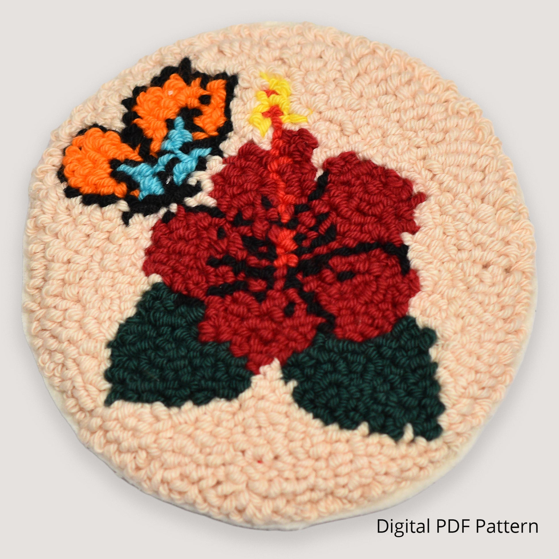 Handmade punch needle coaster featuring a red hibiscus flower with butterfly detail, looped embroidery texture on a neutral beige background, digital PDF punch needle pattern.