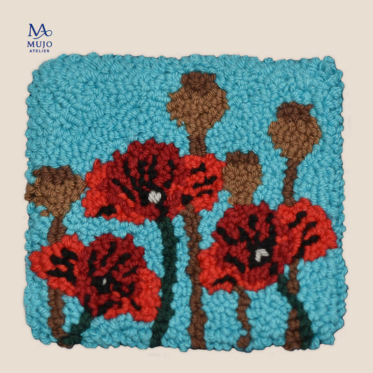 Punch needle pattern featuring three red poppy flowers and brown seed pods on a bright turquoise blue background, with textured yarn loops and green stems.