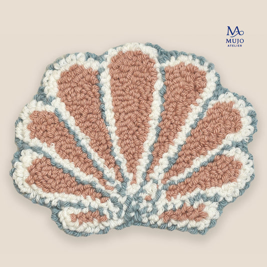 Pastel seashell punch needle coaster pattern in blush pink, white, and soft blue on a neutral beige background with Mujo Atelier branding. Digital PDF embroidery pattern for DIY punch needle craft.