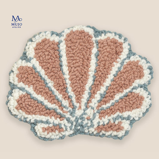 Pastel seashell punch needle coaster pattern in blush pink, white, and soft blue on a neutral beige background with Mujo Atelier branding. Digital PDF embroidery pattern for DIY punch needle craft.