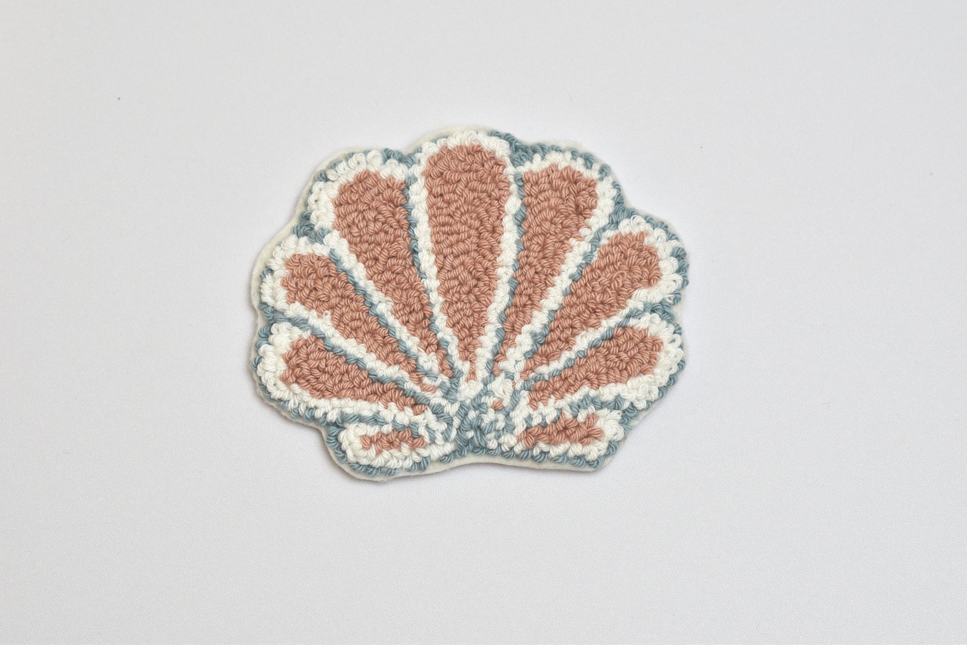 Shell-shaped rug with pink interior and blue exterior on a light gray background