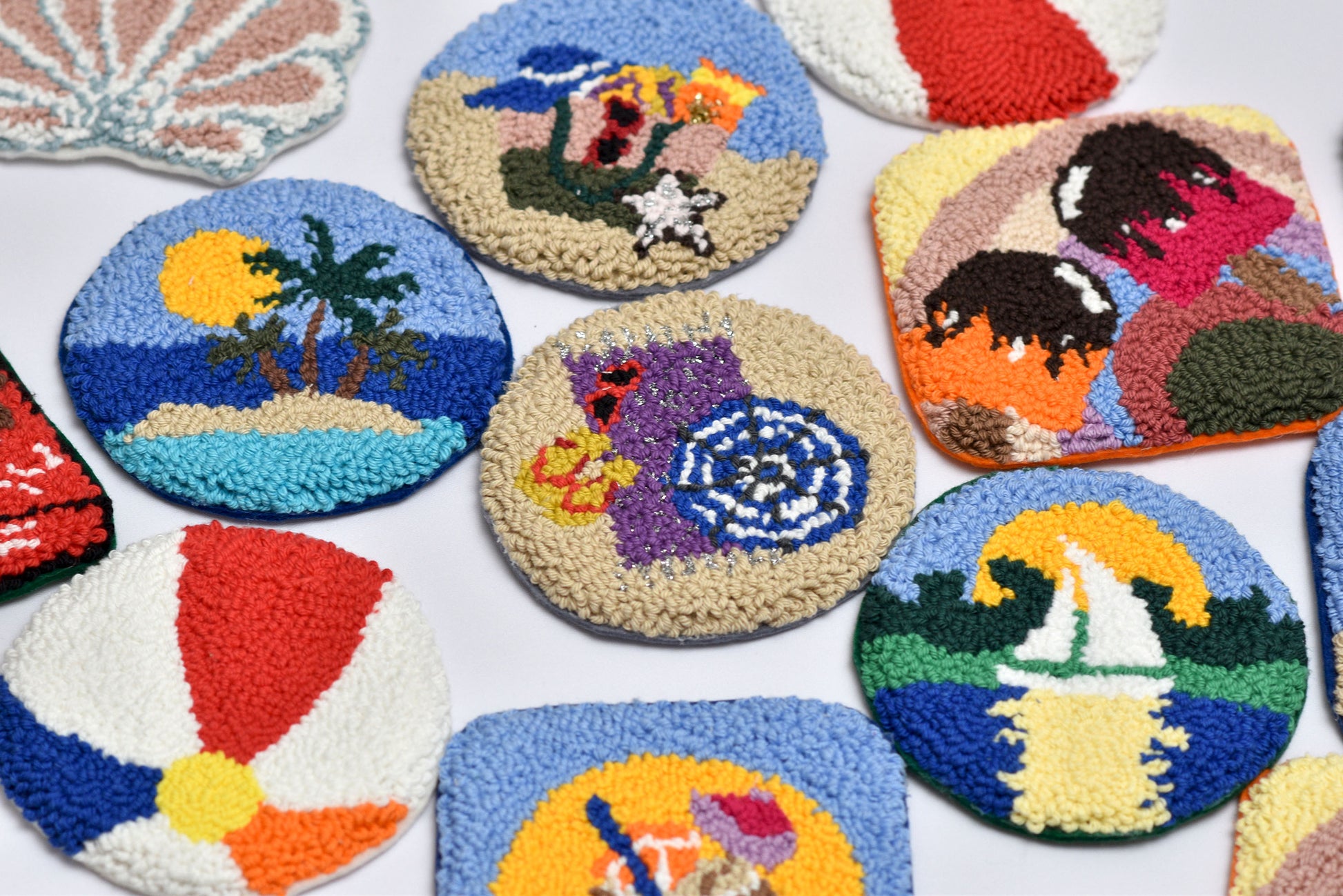 Collection of colorful embroidered coasters with various designs on a white background