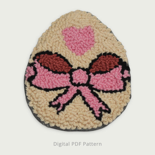 Punch needle Easter egg coaster featuring a pink bow and heart motif, textured handmade look, digital PDF punch needle pattern