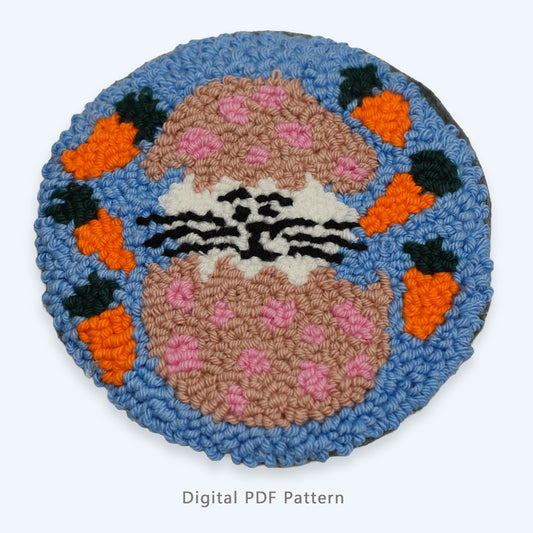 Easter bunny punch needle coaster digital PDF pattern featuring a bunny in a cracked egg with carrots on a blue background.