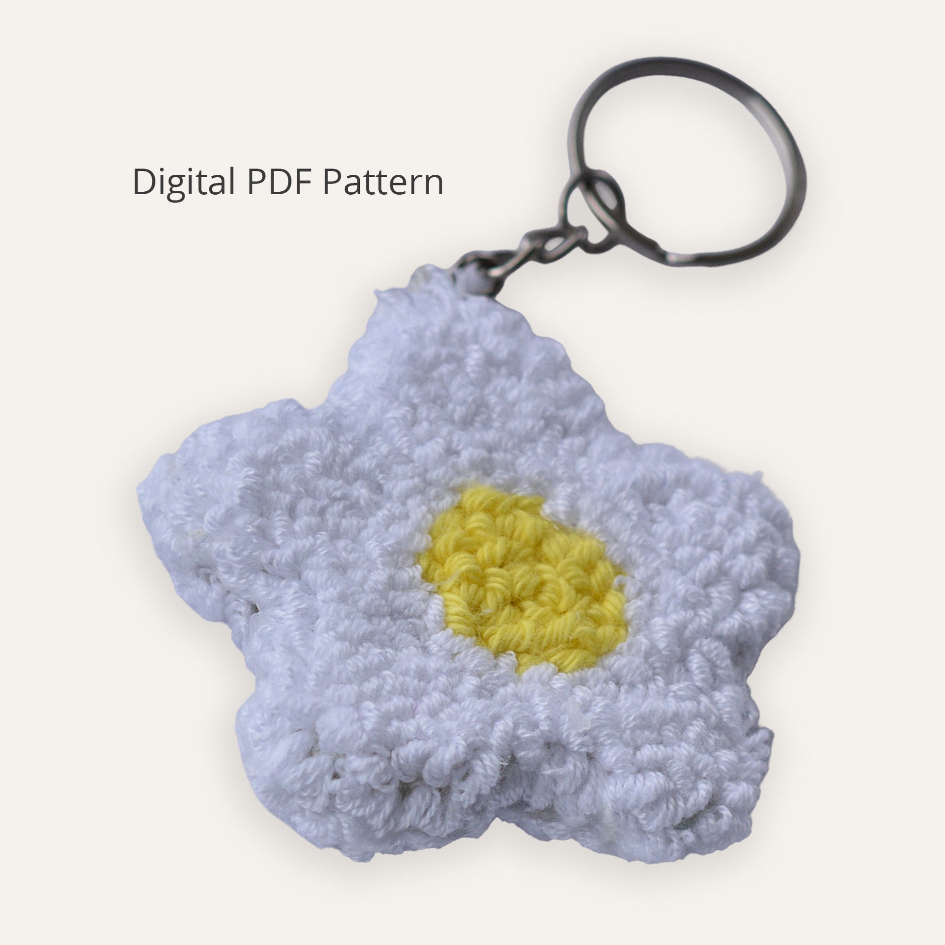 Punch needle daisy keychain digital PDF pattern showing a white embroidered flower with a yellow center and metal keyring on a neutral background