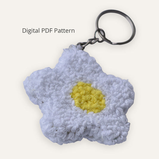 Punch needle daisy keychain digital PDF pattern showing a white embroidered flower with a yellow center and metal keyring on a neutral background
