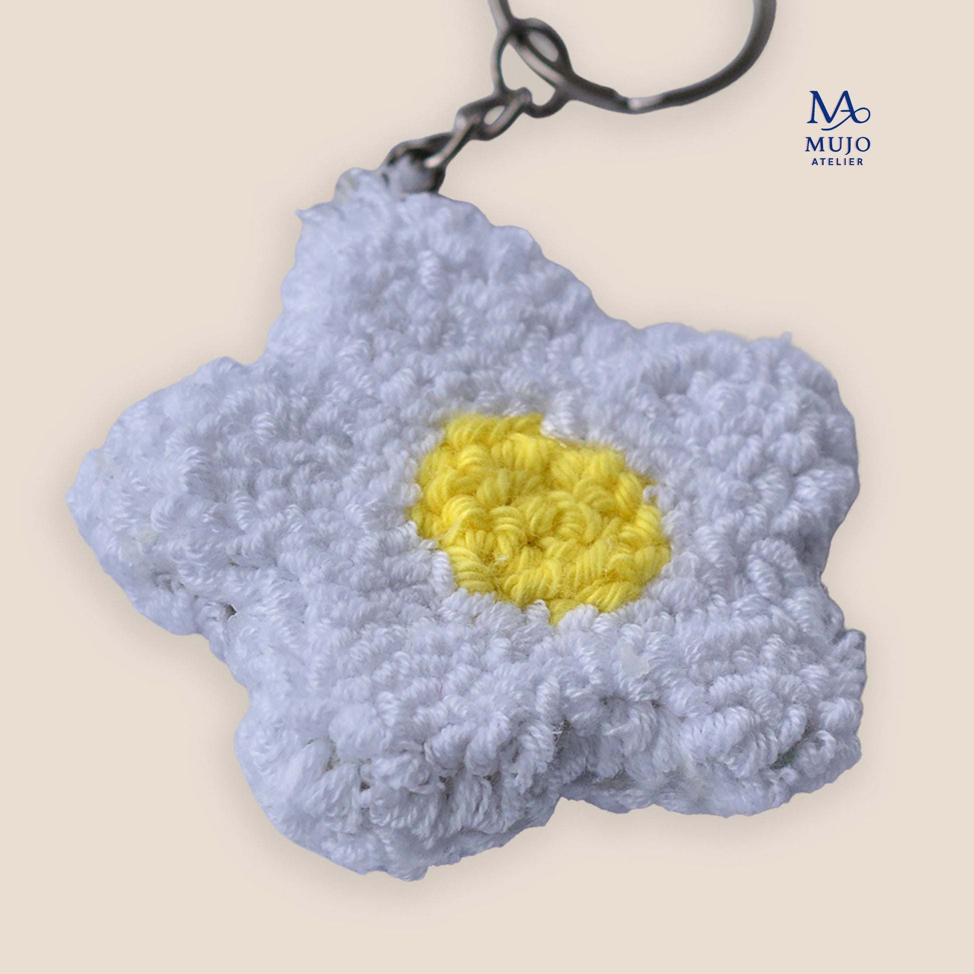 White daisy punch needle keychain pattern with a yellow center shown on a neutral beige background with Mujo Atelier branding. Digital PDF embroidery pattern for DIY punch needle craft.